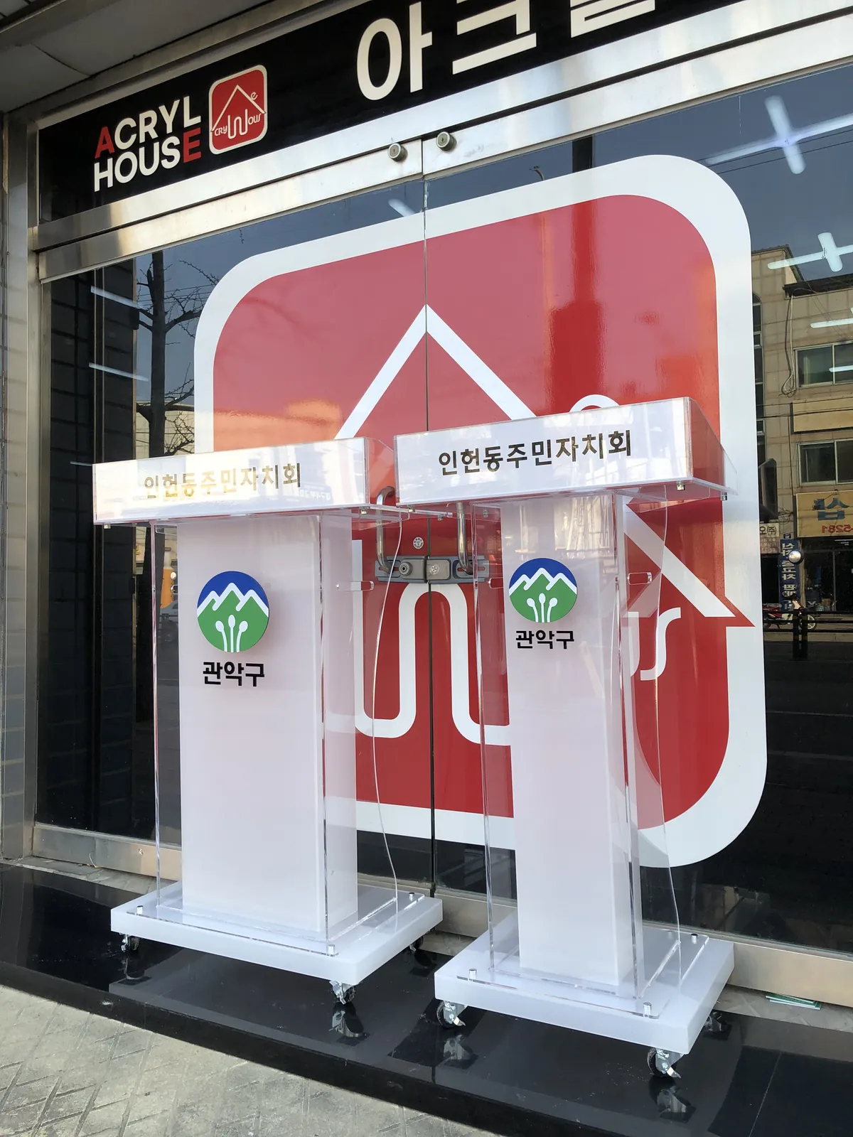상단에 인헌동주민자치회 문구를 넣고 관악구 로고를 붙인 투명과 서리 아크릴 강연대와 사회대