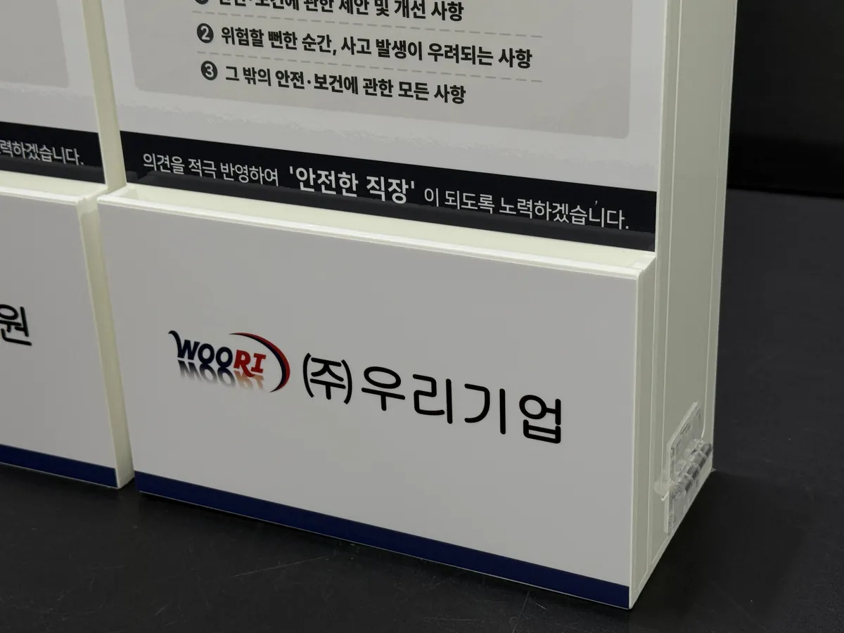 (주)우리기업 CI 로고가 인쇄된 하단 포켓과 측면 경첩 클로즈업
